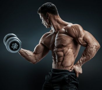 Handsome power athletic man in training pumping up muscles with dumbbell. Strong bodybuilder with six pack, perfect abs, shoulders, biceps, triceps and chest